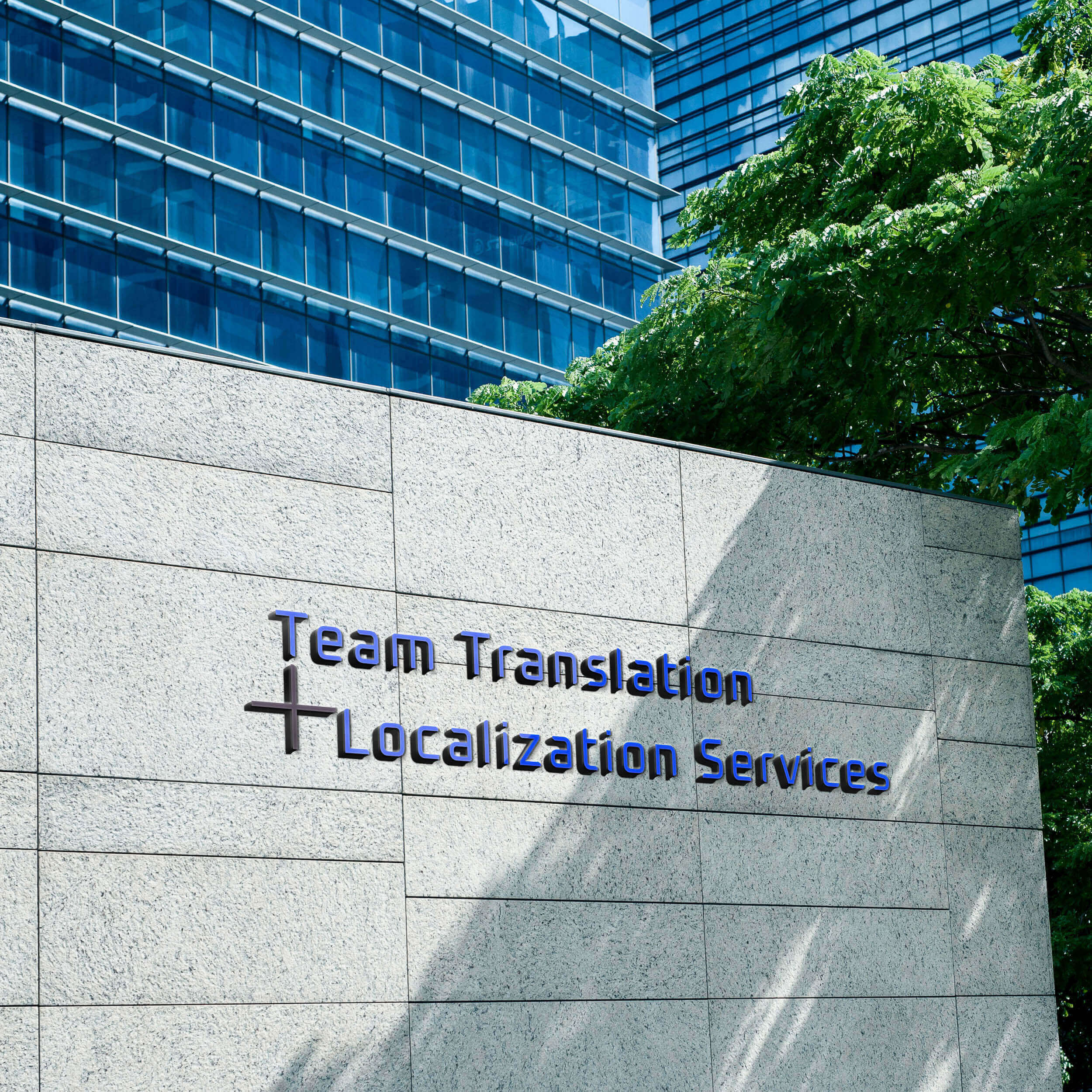 Das Logo von Team Translation and Localization Services, das durch den Service Logo Design Stuttgart entstand. Das Logo ist auf einer Mauer vor einem Gebäude angebracht.